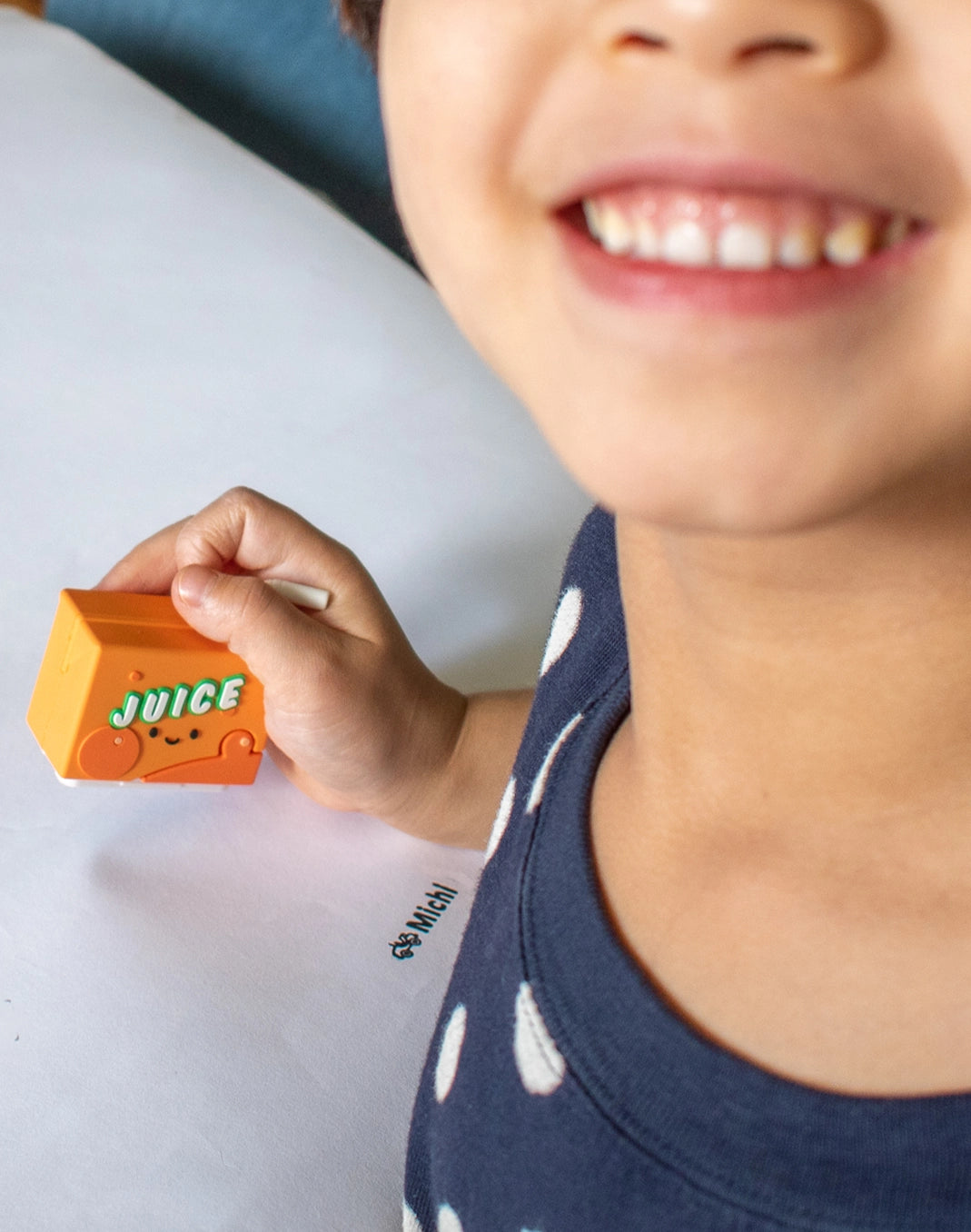Boy with smiley face holding the Juicy Sip name stamp with an imprint on paper